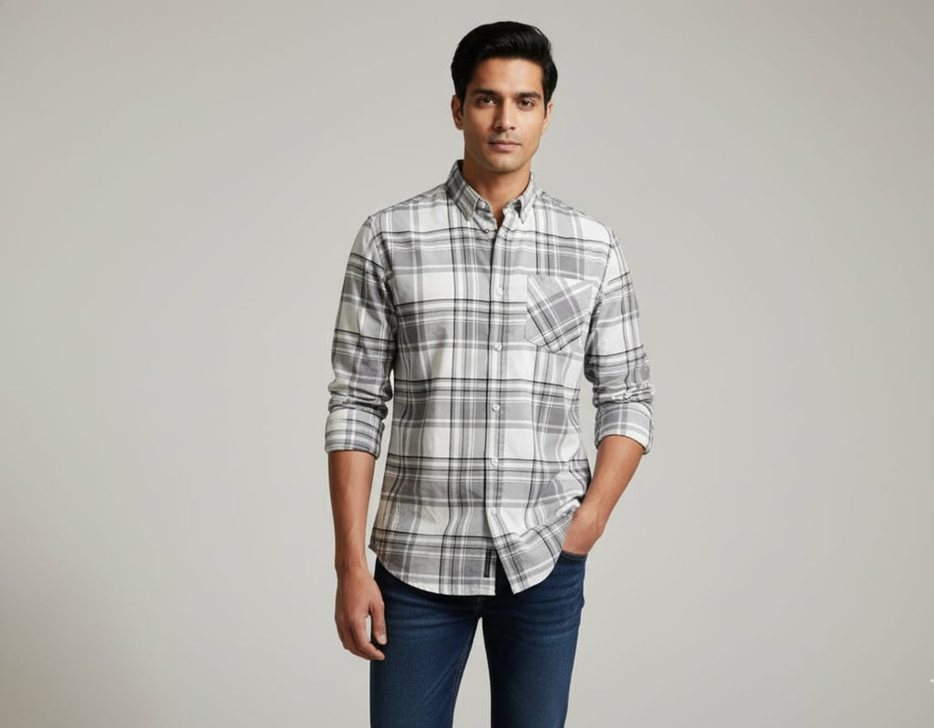 Man wearing a gray plaid shirt and blue jeans against a plain background